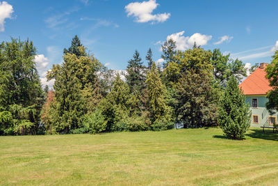 Scenic view of green landscape and trees against sky