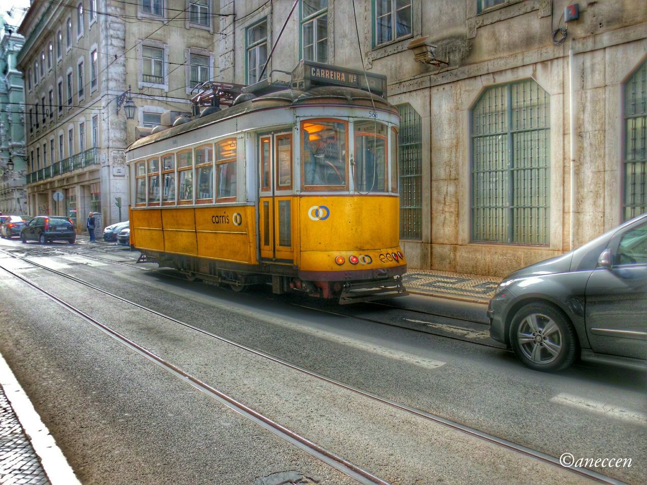 transportation, mode of transport, architecture, land vehicle, building exterior, built structure, car, street, road, public transportation, city, railroad track, travel, road marking, outdoors, train - vehicle, yellow, rail transportation, no people, day