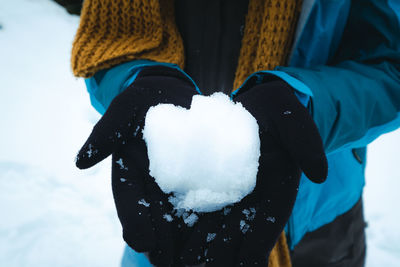 Midsection of woman holding snow during winter