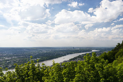 River rhein in western germany flowing along the city against the sky with clouds. visible barges.