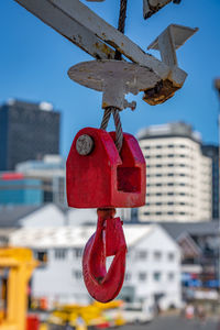 Close-up of red bell hanging on building against sky