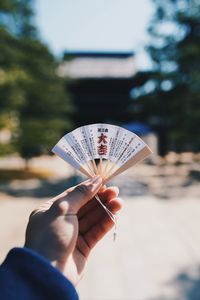 Close-up of hand holding small folding fan