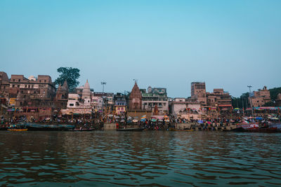 Buildings by river against clear sky