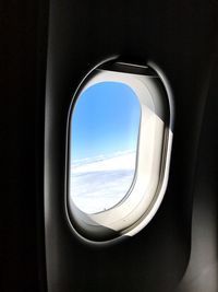 Reflection of clouds in sky seen through airplane window