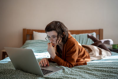 Concentrated teen girl reading book online, scrolling social networks in internet on laptop computer