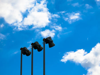 Low angle view of street lights against blue sky