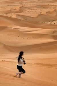 Side view of woman with camera walking in desert