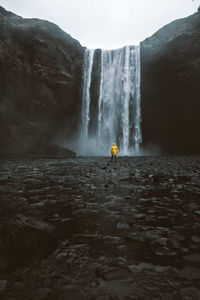 Rear view of man standing at waterfall