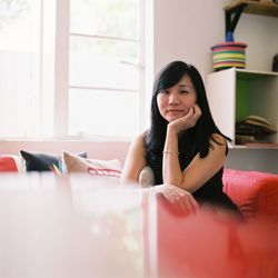 Portrait of young woman sitting on sofa at home