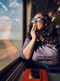 Beautiful young woman looking through train window