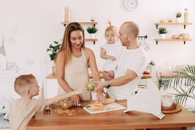 Happy big family of mom dad two kids cooking together and having fun in the kitchen at home