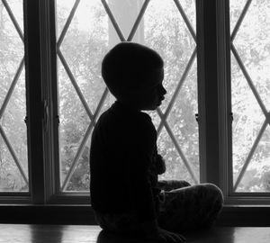 Boy sitting against window