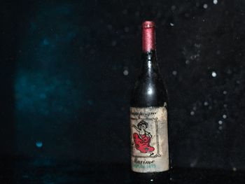 Close-up of glass bottle on table against black background