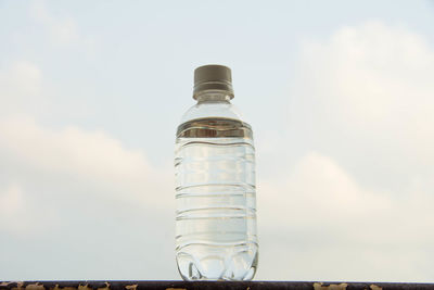 Close-up of water bottle on metal against sky