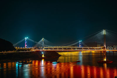 Illuminated bridge over river at night