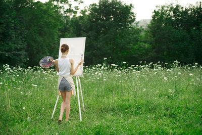 Full length of woman holding umbrella while standing on field