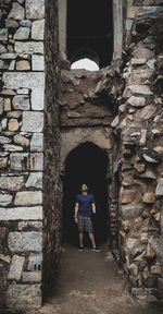 Woman standing by wall of building