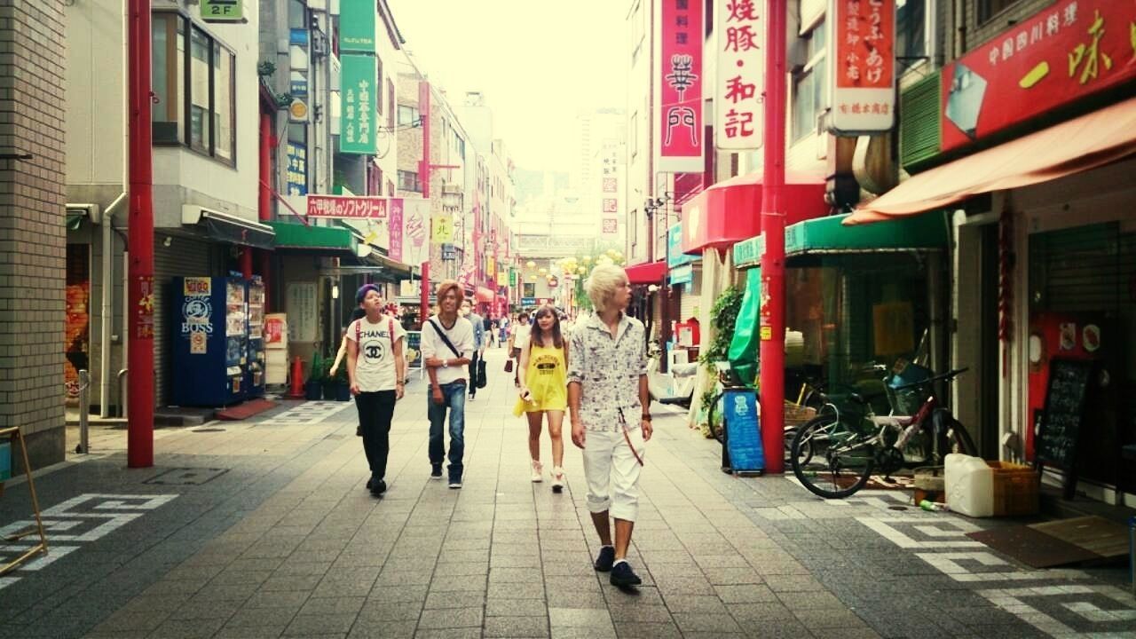 building exterior, architecture, built structure, street, walking, men, person, city, city life, lifestyles, text, the way forward, outdoors, full length, day, store, leisure activity, large group of people, residential structure