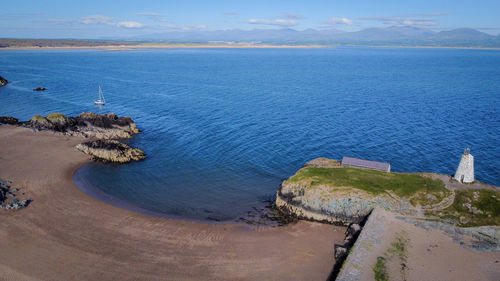 High angle view of lighthouse overlooking the sea against sky and mountains 