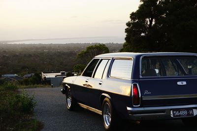 Car on road by sea against sky