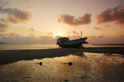 Boat moored on sea against sky during sunset