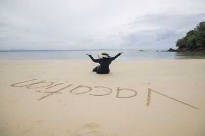 Man with text on sand at beach against sky