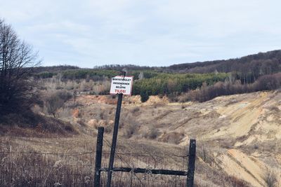 Sign board on wooden post against sky