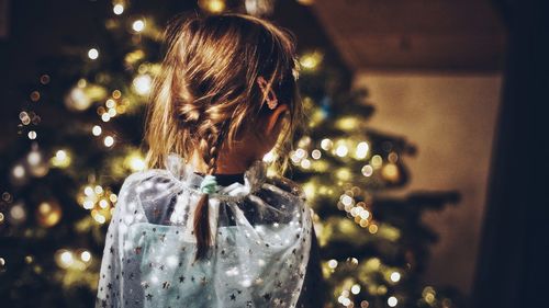 Rear view of girl standing against christmas tree
