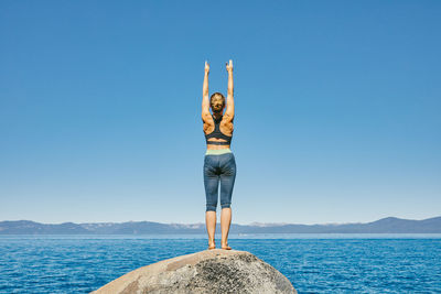 Young woman practicing yoga on lake tahoe in northern california.