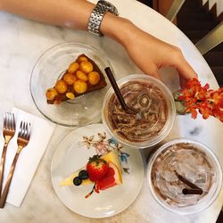 Cropped hand of woman by drink and cake on table