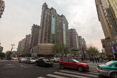 Traffic on city street by buildings against sky