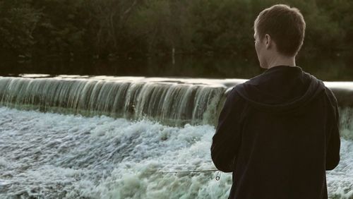 Rear view of man standing against dam