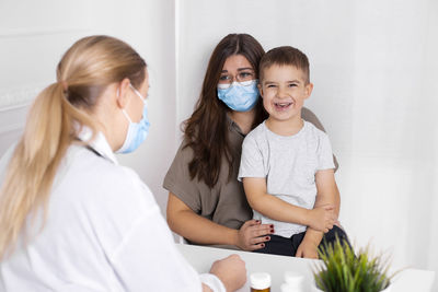 Young brunette woman with little boy having consultation at pediatrician office. doctor, child