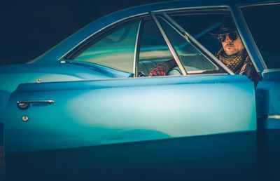 Portrait of man sitting in blue car