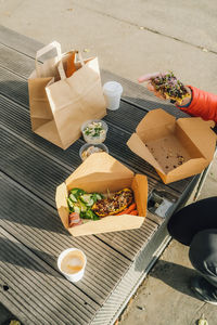 High angle view of male hand holding food outside, take away breakfast.