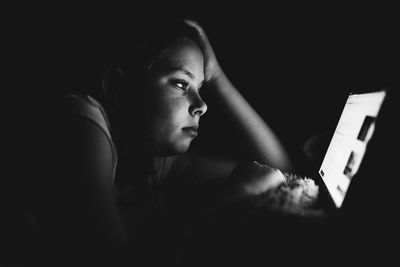 Girl using digital tablet against black background
