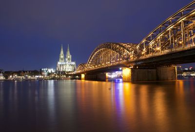 Illuminated hohenzollern bridge over city at night