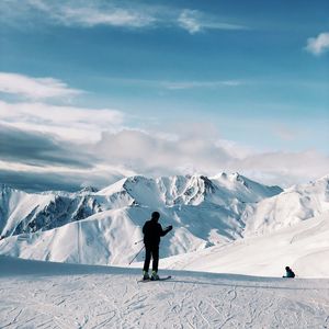 Rear view of person skiing on snowcapped mountain against sky