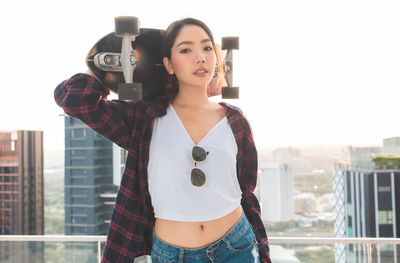 Portrait of young woman photographing against cityscape