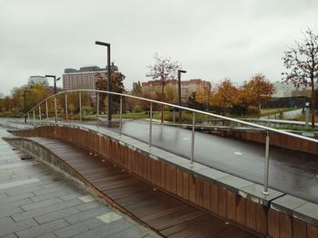 Bridge over footpath in city against sky