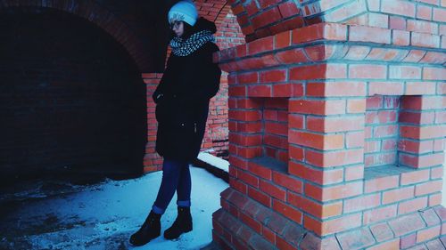 Woman leaning on column at archway during winter