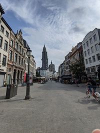 People on street amidst buildings in city against sky