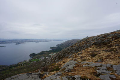 Scenic view of sea by mountain against sky