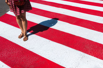 Low section of woman standing on zebra crossing during sunny day