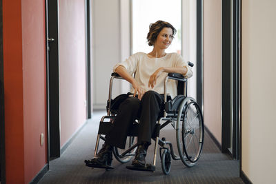 Disabled business woman sitting in wheelchair, with laptop on knees