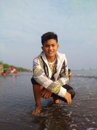 Portrait of young man in sea against sky