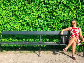 Portrait of woman sitting on bench in park