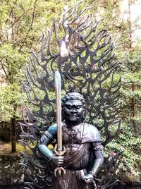 Sculpture of old statue against trees