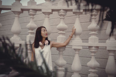 Portrait of young woman standing by railing