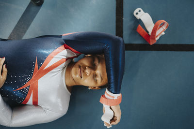 Directly above shot of female teenage athlete with eyes closed resting on floor
